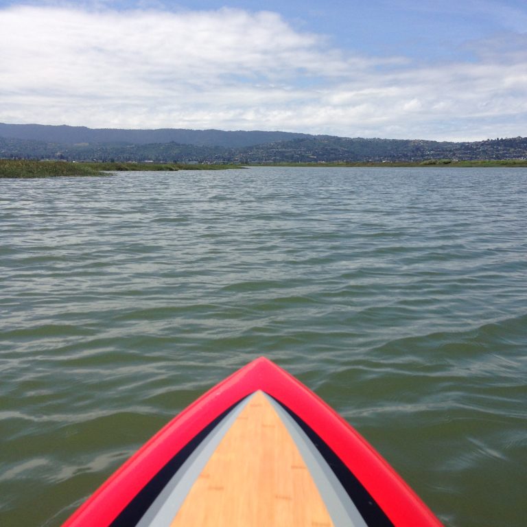 Paddleboard-level view of open water and hills beyond