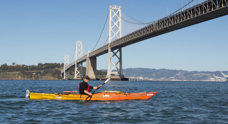 Lone kayaker paddles under Bay Bridge