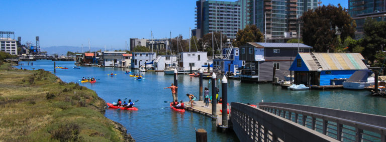 Ramp with railings leading down to dock with kayakers and houseboats in water