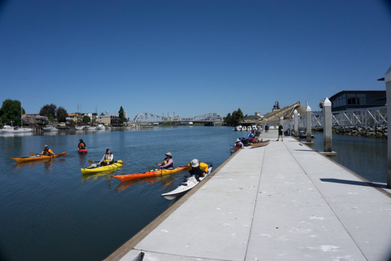 Small group of kayakers pushing off from a low-freeboard dock
