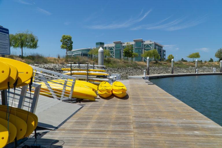 wooden dock with paddle boards and kayaks next to ramp with railings
